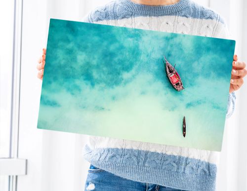 A woman holding a vivid fine art photo print of boats in turquoise water — example of fine art photo printing on paper