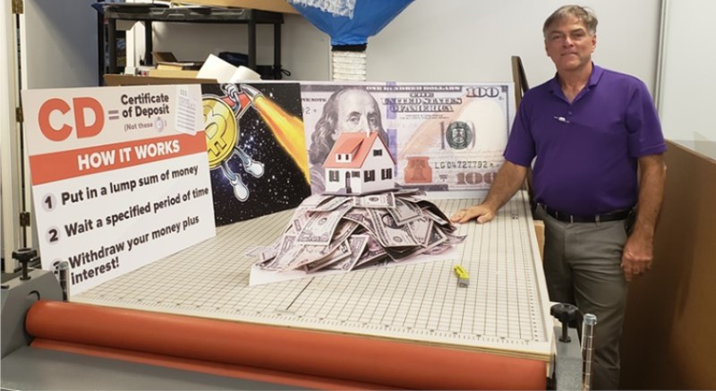 an image showing robert schmidt from gentilly mail and copy center with digital signs printed lying on the table. 